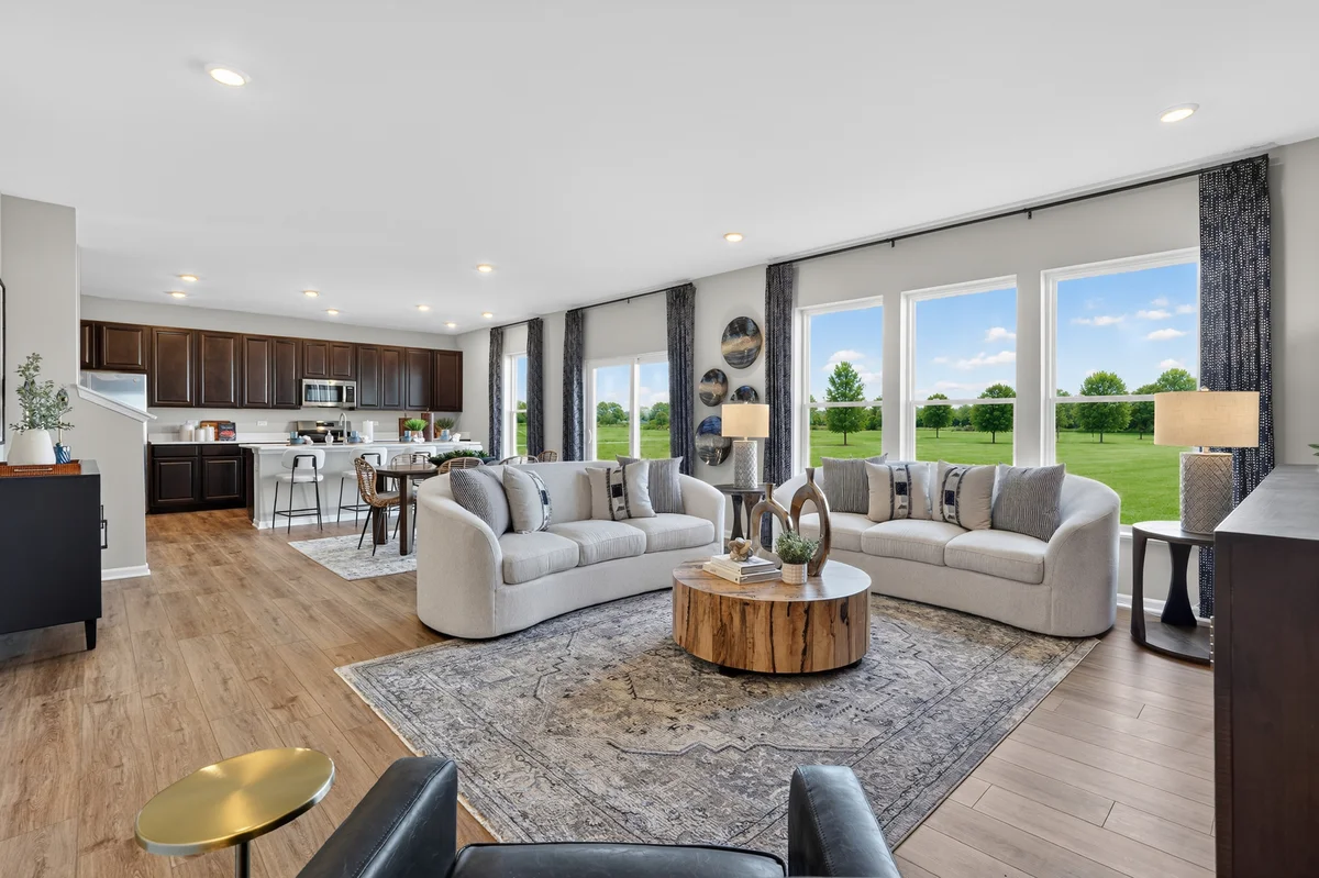 Beautifully staged living room with floor-to-ceiling windows and open-plan kitchen — professional real estate photography