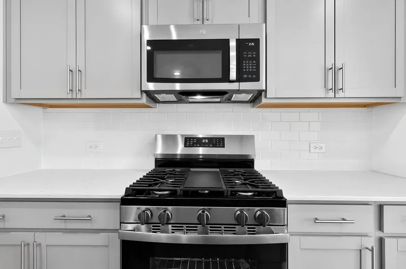 Stainless steel gas range and microwave in a kitchen