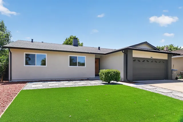 Freshly prepped single-story home with new turf, gravel landscaping and a painted garage door, ready to list