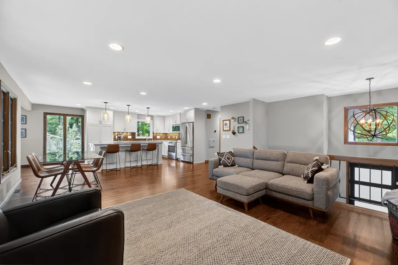 Open-concept living room with a gray sectional, dining area and kitchen island under pendant lights