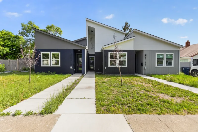 Front exterior of a newly built vacant duplex with overgrown grass