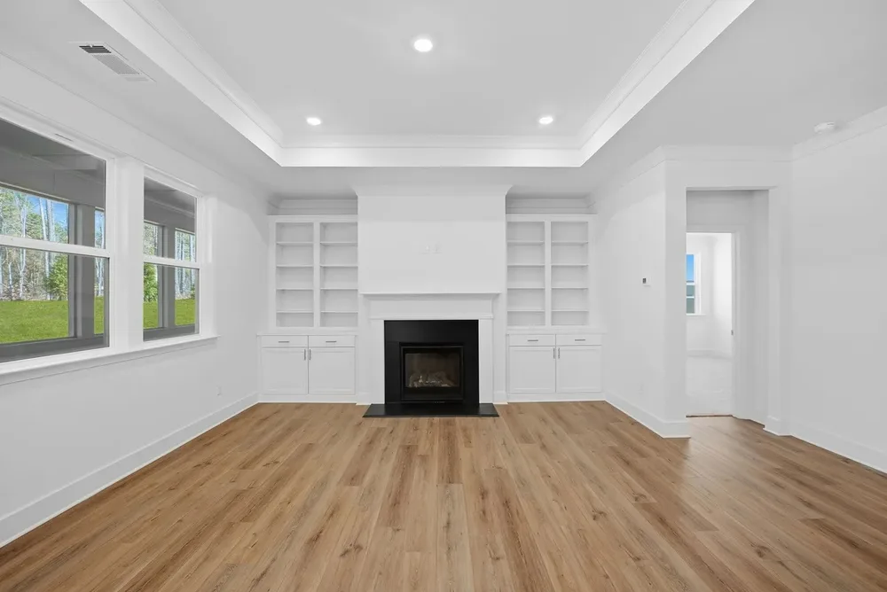 Empty staged living room with a fireplace and built-in shelving, prepared for a real estate listing