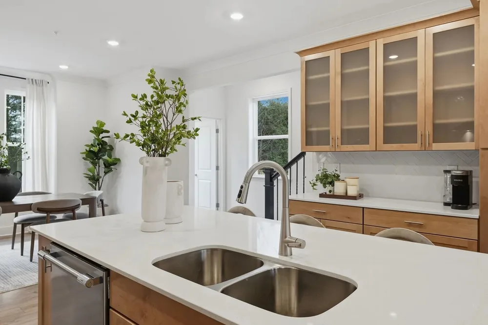 Kitchen island with a stainless steel sink, faucet and cabinetry in a home prepared for sale
